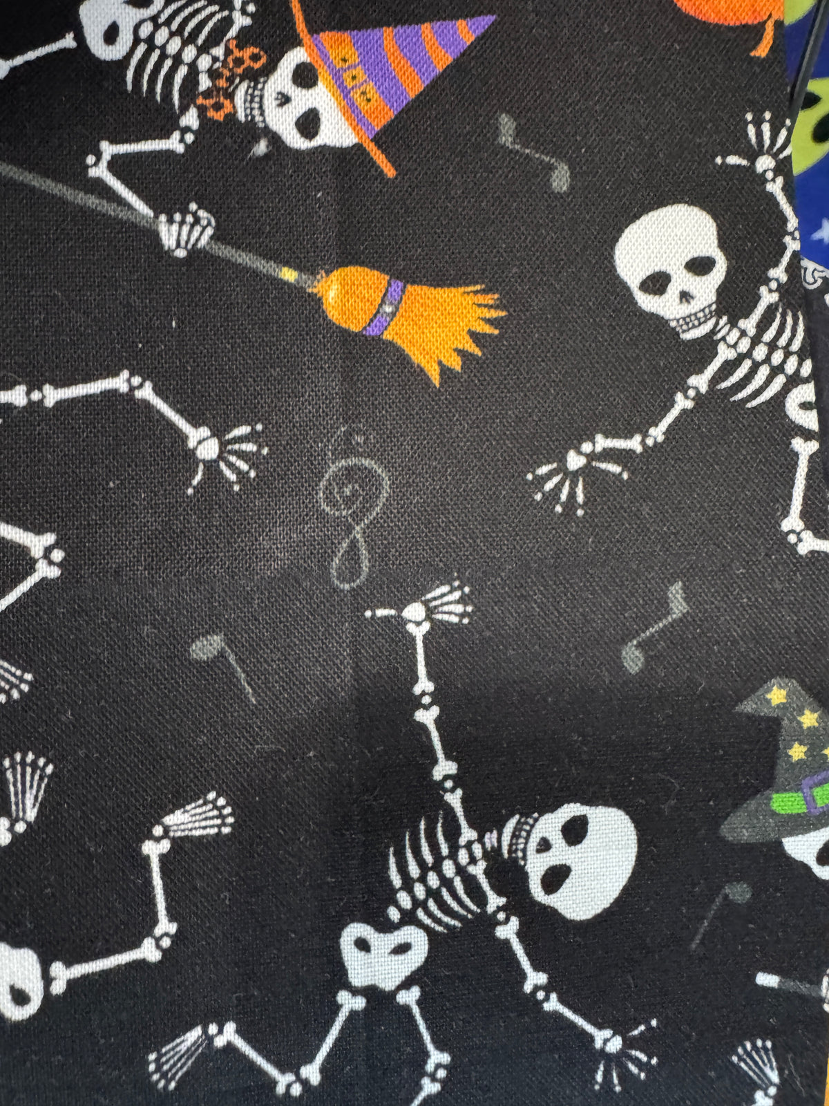 Halloween-themed fabric with skeletons, pumpkins, and brooms on a black background